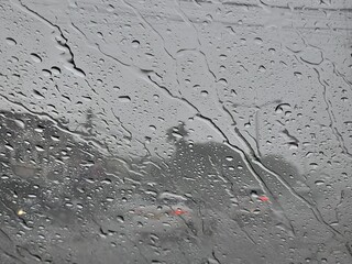 The essence of a rainy day seen through a car window where raindrops on the windscreen blur the world outside.