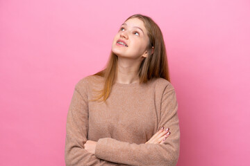 Obraz premium Teenager Russian girl isolated on pink background looking up while smiling