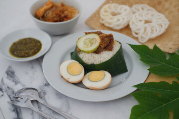rice with meat, egg, crackers, chili sauce and cucumber on a white background