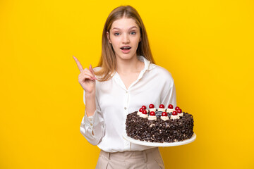 Teenager Russian girl holding birthday cake isolated on yellow background intending to realizes the solution while lifting a finger up