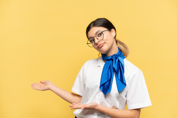 Airplane stewardess isolated on yellow background with surprise expression while looking side