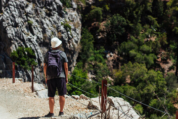 a man with a backpack on his shoulders is traveling on a tourist road around the mountains