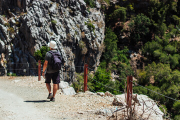a man with a backpack on his shoulders is traveling on a tourist road around the mountains