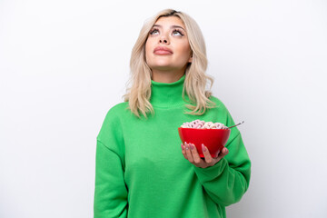 Young Russian woman holding a bowl of cereals isolated on white background and looking up