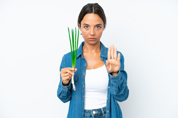 Young hispanic woman holding chive isolated on white background making stop gesture