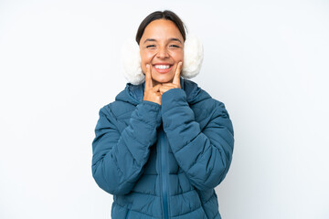 Young hispanic woman wearing a winter earmuffs isolated on white background smiling with a happy...