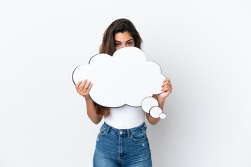 Young caucasian woman isolated on white background holding a thinking speech bubble and hiding behind it