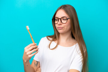 Young Lithuanian woman brushing teeth over isolated background with sad expression