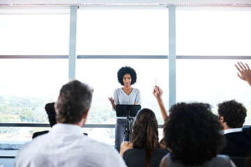 Presentation, conference and black woman with question from business people for discussion, meeting and speech. Entrepreneurship, audience and men and women ask in seminar, tradeshow and convention