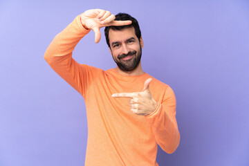 Caucasian handsome man over isolated purple background focusing face. Framing symbol