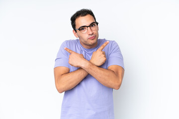 Young caucasian man isolated on white background pointing to the laterals having doubts