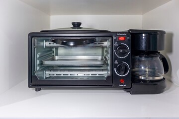 A multifunctional breakfast maker with coffee maker, frying pan, and toaster oven.