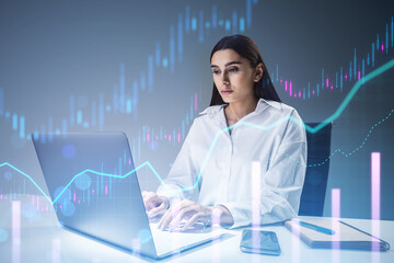 Professional woman using a laptop with digital graphs overlaid on a blue background, indicating data analysis