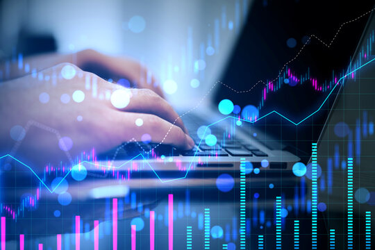 An individual using a laptop with overlaying digital financial graphs, representing data analysis or stock market concept on a dark, bokeh background