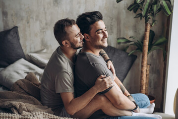 Two homosexual male partners taking care of each other. Lovely gay couple have warm cuddle, having...