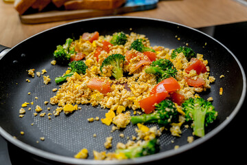 Chef at the kitchen preparing tofu scramble with vegetables