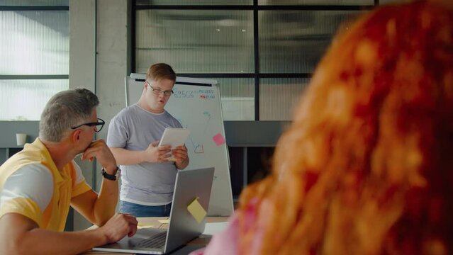 Man with disability in front of people sitting by desk