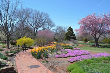 Fototapeta premium A bright spring garden with colorful flowers and the rejuvenating energy of nature. Bright flowers fill the scene under a blue sky