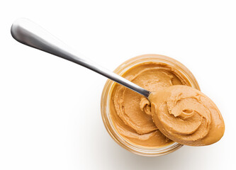 Peanut butter in glass jar and spoon isolated on white background, top view, copy space. American dessert concept
