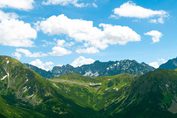 Beautiful mountain landscape in summer. Green grass, high rocks, blue sky and white clouds. Natural background. Tatra Mountains
