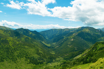 Fototapeta premium Beautiful mountain landscape in summer. Green grass, high rocks, blue sky and white clouds. Natural background. Tatra Mountains
