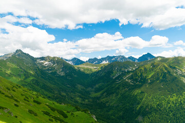 Fototapeta premium Beautiful mountain landscape in summer. Green grass, high rocks, blue sky and white clouds. Natural background. Tatra Mountains
