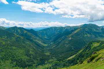 Beautiful mountain landscape in summer. Green grass, high rocks, blue sky and white clouds. Natural background. Tatra Mountains