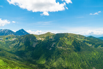 Naklejka premium Beautiful mountain landscape in summer. Green grass, high rocks, blue sky and white clouds. Natural background. Tatra Mountains