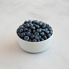 Organic Blueberries in a Bowl on a gray background, side view.