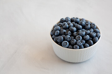 Organic Blueberries in a Bowl on a gray background, side view. Copy space.