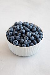 Organic Blueberries in a Bowl on a gray background, side view.