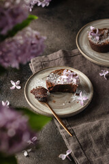 Fresh homemade chocolate muffin with spoon close up on a rustic plate with lilac flowers