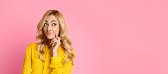 This image features a young woman with long blonde hair wearing a yellow shirt. She is standing in front of a pink background and is looking off to the side, appearing thoughtful.