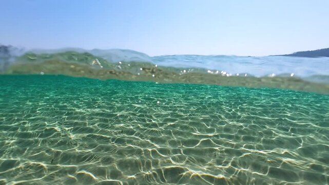 Half underwater slow motion turquoise sea water at the exotic sandy beach on the tropical island. Idyllic view of ocean and the white sand