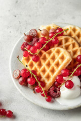 Homemade waffles with summer berries and a scoop of ice cream in plate on grey table close up. Heart shaped waffles