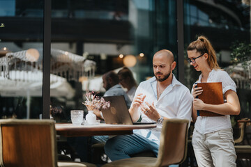 Business workers are collaborating together on a project in a coffee bar, brainstorming ideas and sharing knowledge for solutions, working remotely.