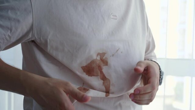 A dirty T-shirt on a man.
The careless man spilled the drink on himself.
Stain on a T-shirt.
Mud, swamp, stain, drink, spill