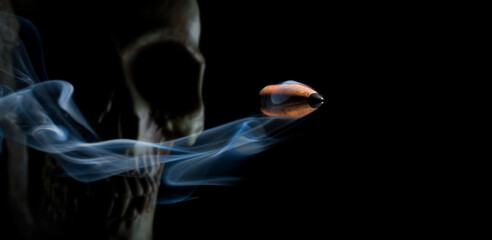 Smoking fast bullet with human skull behind on a black background depicting gun violence or war.