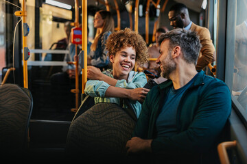 Friends laughing and talking in a crowded bus, she with smart phone