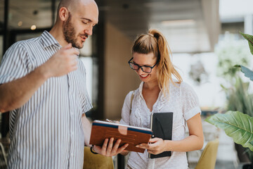 Two colleagues discussing work with tablets in a modern office environment. Professional interaction, collaboration, and teamwork.