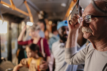 focus on retired senior man holding on to the handle on the bus