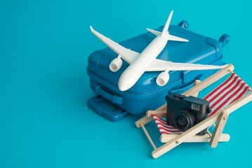 Travel suitcase, airplane, digital camera and red beach chair on blue background copy space. Travel...