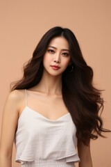 Naklejka premium Portrait of a young Asian woman with long, flowing hair wearing a white camisole