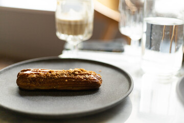 eclair with salted caramel on a gray plate on the table
