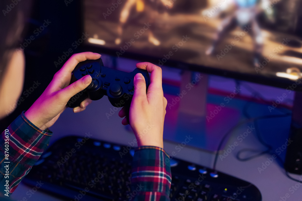Fototapete a persons hands hold a black video game controller, with their fingers resting on the buttons, playi