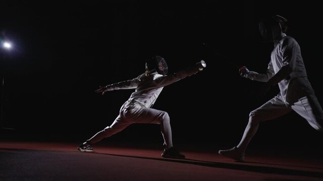 Workout Of Two Professional Fencers In Darkness, Motivated Sportsmen Fighting By Epee Or Sabre