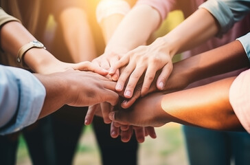 Multiple hands from a diverse group of people stacked together in a gesture of teamwork, unity, and collective effort