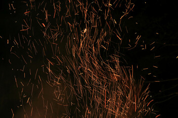 Bright burning Red and Orange Contrasting Sparks of Huge Crackling Bonfire whirl Upward against the...