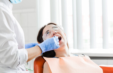 Smiling Patient During Dental Checkup. A dentist in blue gloves treating a smiling patient who is...