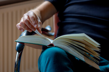 Hobby, Leisure activities concept, A man with casual trousers and black t-shirt sitting on the chair with a book on his lap, Staying home and reading book in living room, Study, learning and cultivate